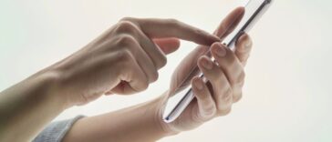Young woman's hands using a portable information device on white background.