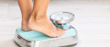 Woman standing on scale, close-up of legs and feet.