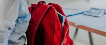 Student looking for something in her red backpack.