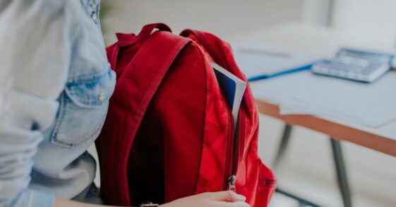 Student looking for something in her red backpack.