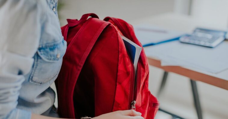 Student looking for something in her red backpack.
