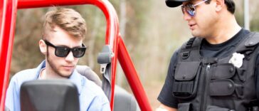 Friendly Latin American police office stops a young man on a rural road. The young man drives an off road vehicle faster than the speed limit and gets a friendly reminder from the policeman.