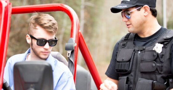 Friendly Latin American police office stops a young man on a rural road. The young man drives an off road vehicle faster than the speed limit and gets a friendly reminder from the policeman.