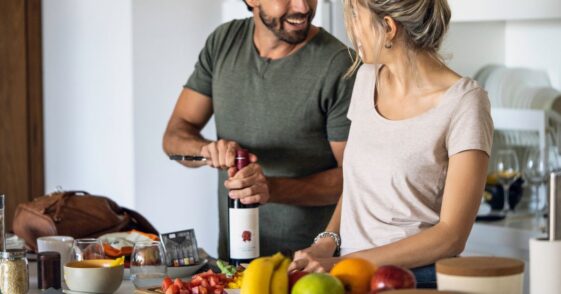 Smiling young couple preparing food in kitchen at home.