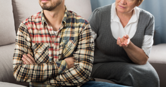 adult son argues with his mother while seated on couch