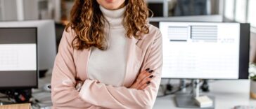 Portrait of a business woman standing in the office with arms crossed, looking at camera, smiling.