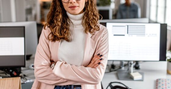 Portrait of a business woman standing in the office with arms crossed, looking at camera, smiling.