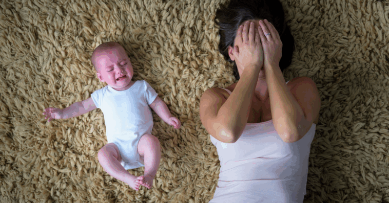 upset mother laying on floor next to crying infant