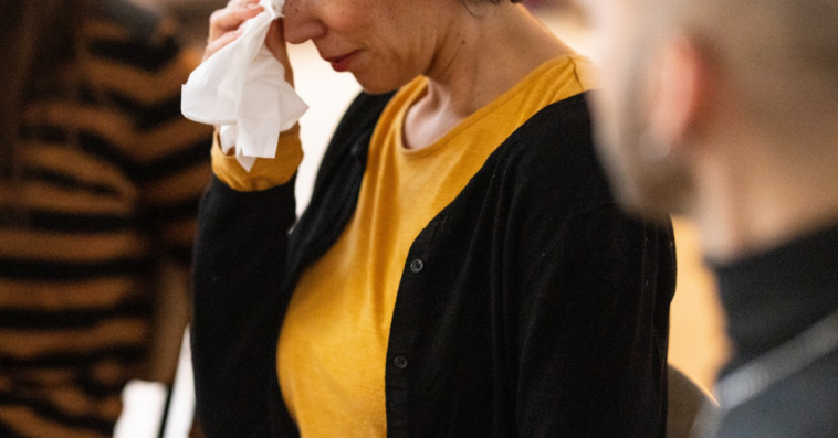 crying older woman flanked by two people