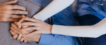 healthcare worker holding older man's hands