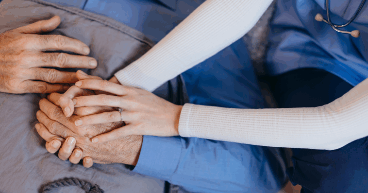 healthcare worker holding older man's hands