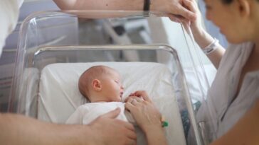 Stock photo of parents looking over their newborn.