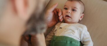 Portrait of cute calm baby lying on sofa, father caressing his soft cheek