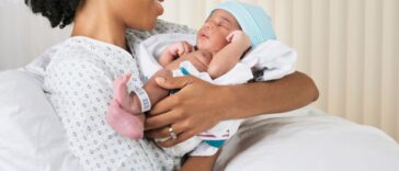 Smiling mother holding newborn baby in hospital.