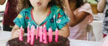 A small group of people, family, children, food, birthday cake, blowing out the candles.