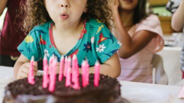 A small group of people, family, children, food, birthday cake, blowing out the candles.