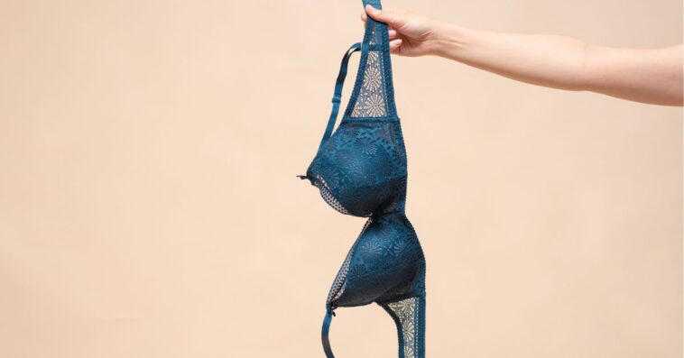 Woman is showing off a new blue bra in the hand. Choosing a new bra concept.