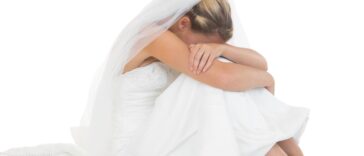 Unhappy blonde bride sitting on floor hiding her face.