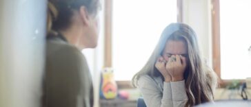 Displeased teenage girl talking to therapist at wellness center.