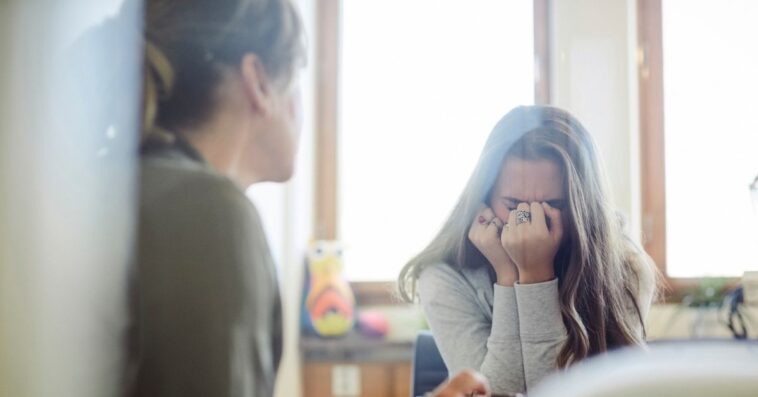 Displeased teenage girl talking to therapist at wellness center.