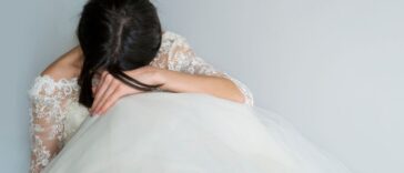 Beautiful Tired and Sad Bride sits on the floor with her head in her lap.
