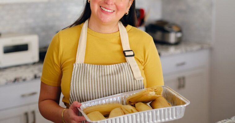 An adult woman making tamales and serving her family in a home kitchen.