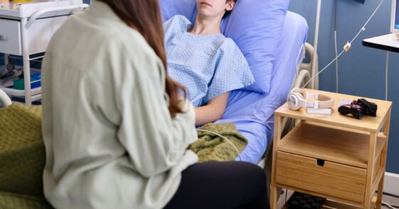 Portrait of a male teenager talking with his friend while lying in the hospital.