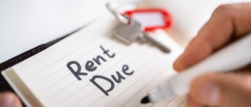 A man writing "Rent Due" on a pad of paper.
