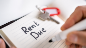 A man writing "Rent Due" on a pad of paper.