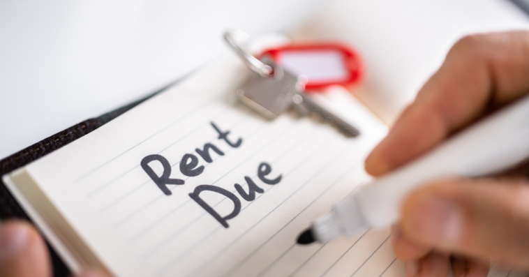 A man writing "Rent Due" on a pad of paper.