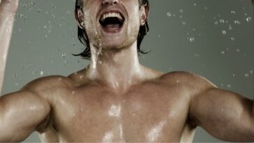 Portrait of young, muscular man splashing his face with water.