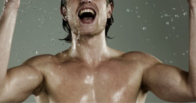 Portrait of young, muscular man splashing his face with water.