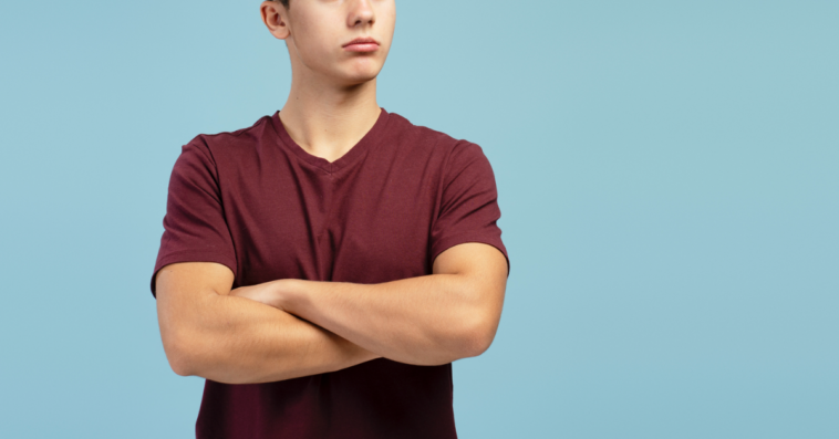 A teenage boy with his arms crossed.