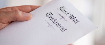 Up close shot of a man's hand holding a last will and testament.