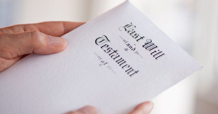 Up close shot of a man's hand holding a last will and testament.