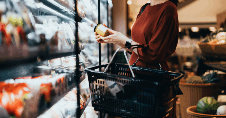 A woman looking at a jar in an aisle in the supermarket.