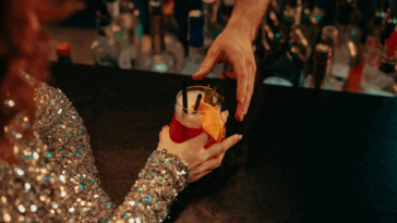 A woman getting a cocktail sitting at a bar.