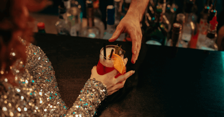 A woman getting a cocktail sitting at a bar.