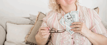 A woman holding a fan of paper bills to her chest.