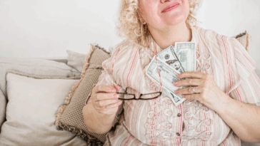 A woman holding a fan of paper bills to her chest.