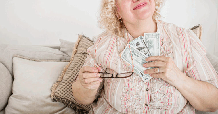 A woman holding a fan of paper bills to her chest.