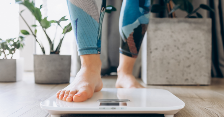 A woman stepping on a scale.