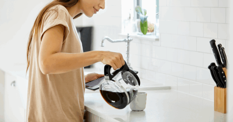 A woman pouring coffee into a mug at the kitchen counter.