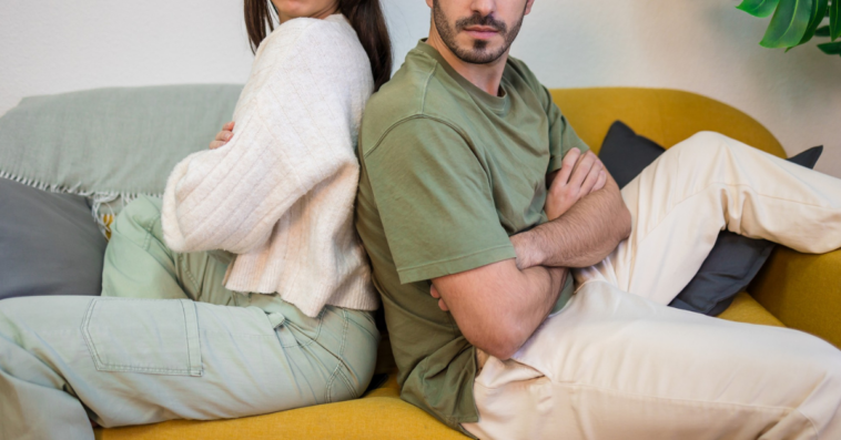 unhappy couple seated back to back with crossed arms