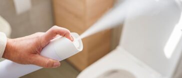 Woman's hand spraying air freshener to remove unpleasant odors of the bathroom.