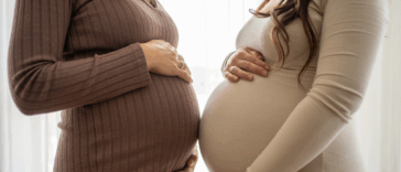 Two pregnant women holding their stomachs.