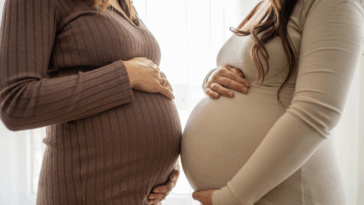 Two pregnant women holding their stomachs.