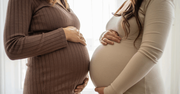Two pregnant women holding their stomachs.