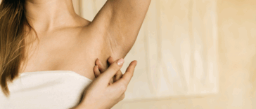 A woman lifting up her arm and revealing her armpit.