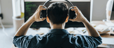back of seated man's head as he puts on headphones